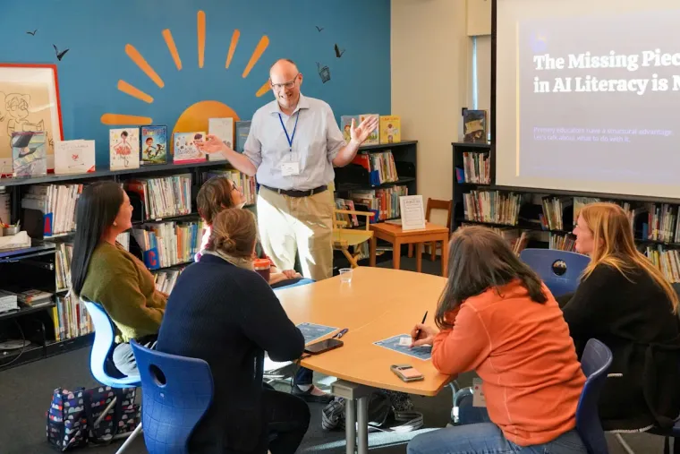 Ian McCullough leading a small-group session on AI literacy at The Learning Frontier, with his title slide visible on screen