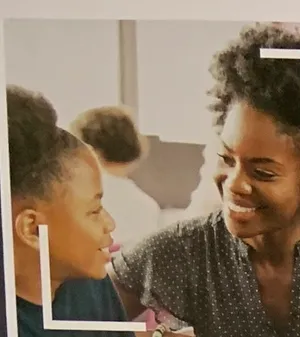 A mentor and student sharing a laugh, one of the concepts pinned to a campaign creative-review wall